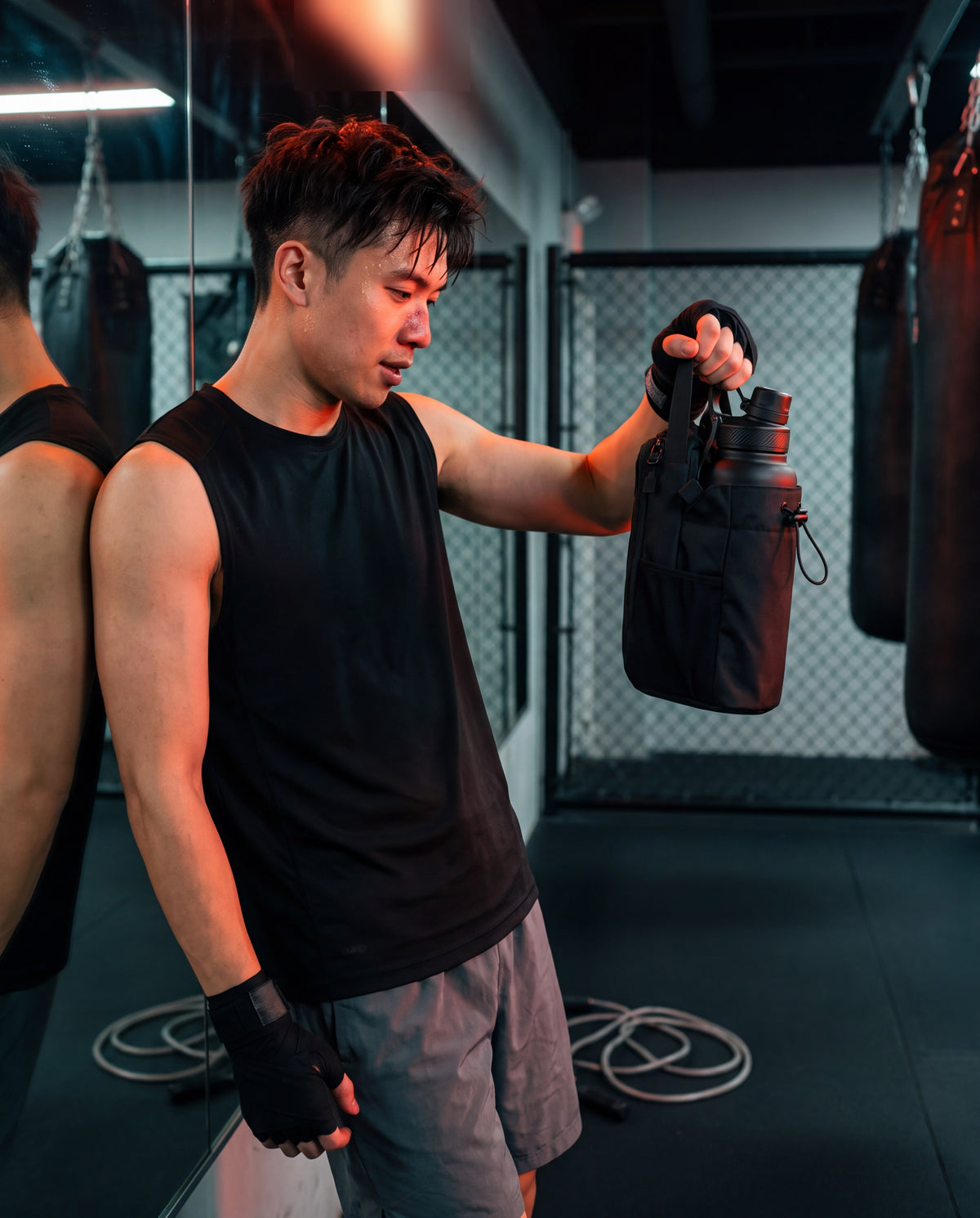Man in a boxing gym holding the bottle bag by its top handle